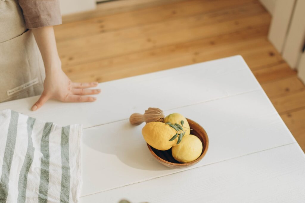 Lemon bowl on table with woman's hand and dishtowel