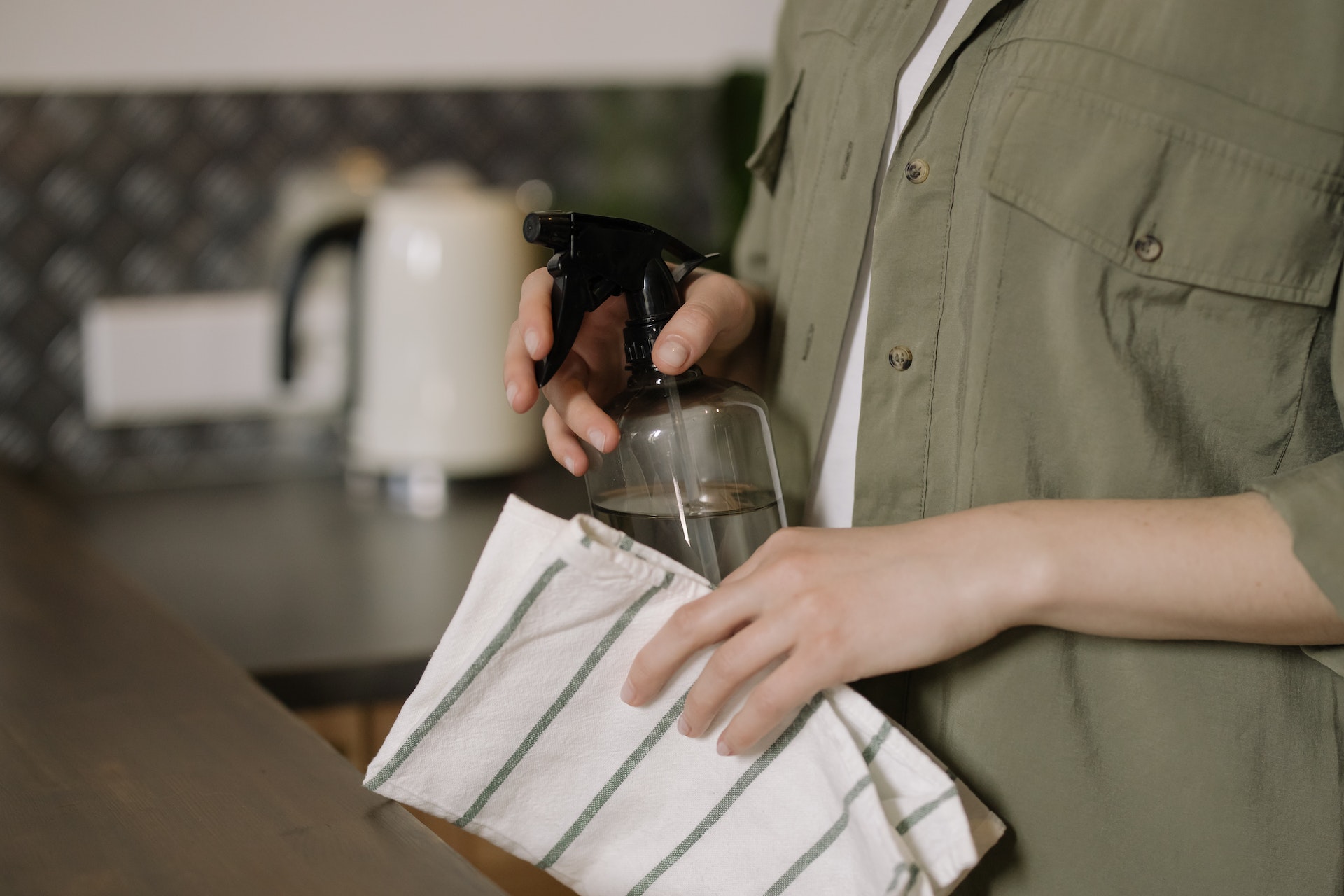 Woman Spraying Countertop with Cleanser and Towel