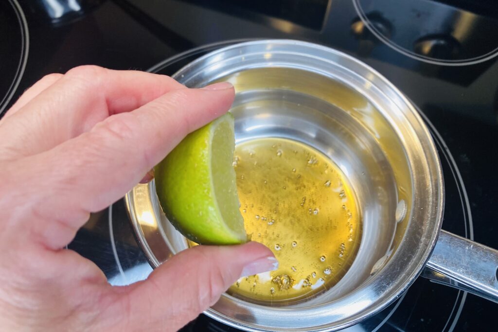 Hand Squeezing Lime Wedge into saucepan of Honey