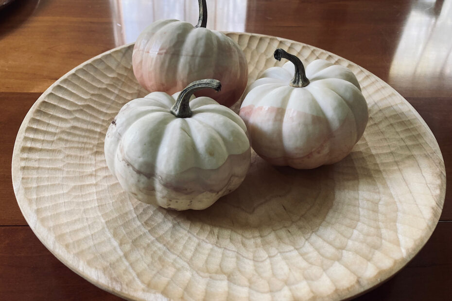 Minimal enamel dipped pumpkins in a carved wooden bowl.
