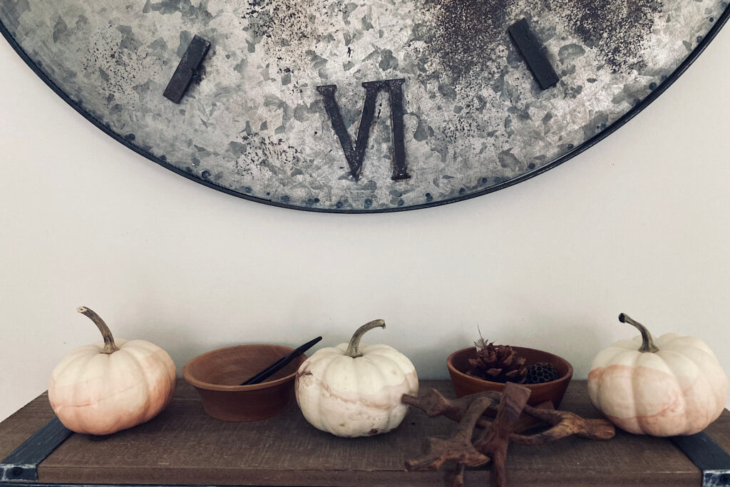 Dipped pumpkins on shelf below clock.