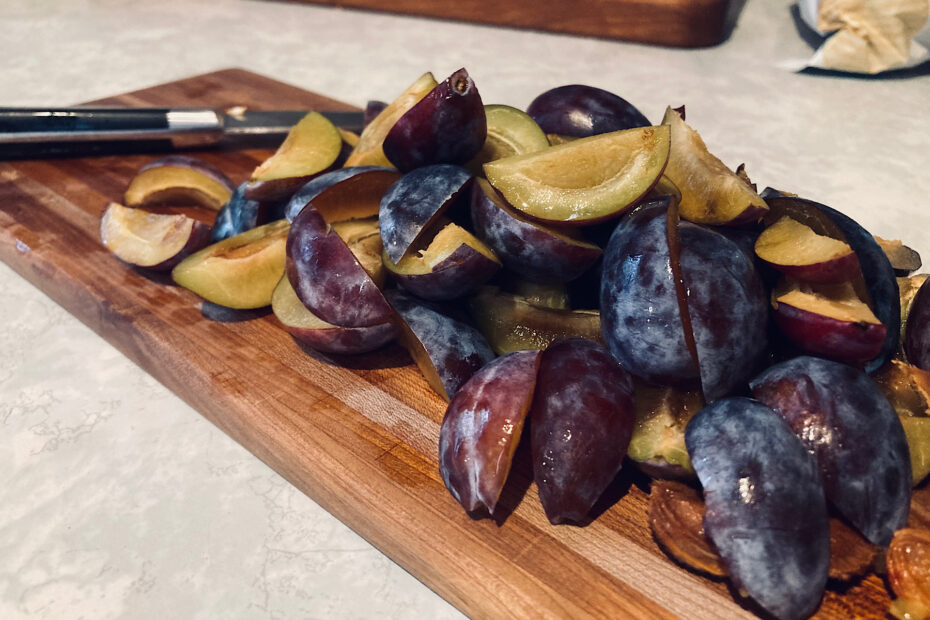 Plums sliced on wooden cutting board