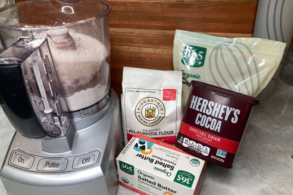 Flour, Butter, Sugar and Cocoa next to Food Processor