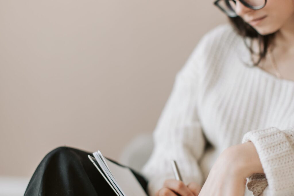 Woman in white sweater and glasses making a list