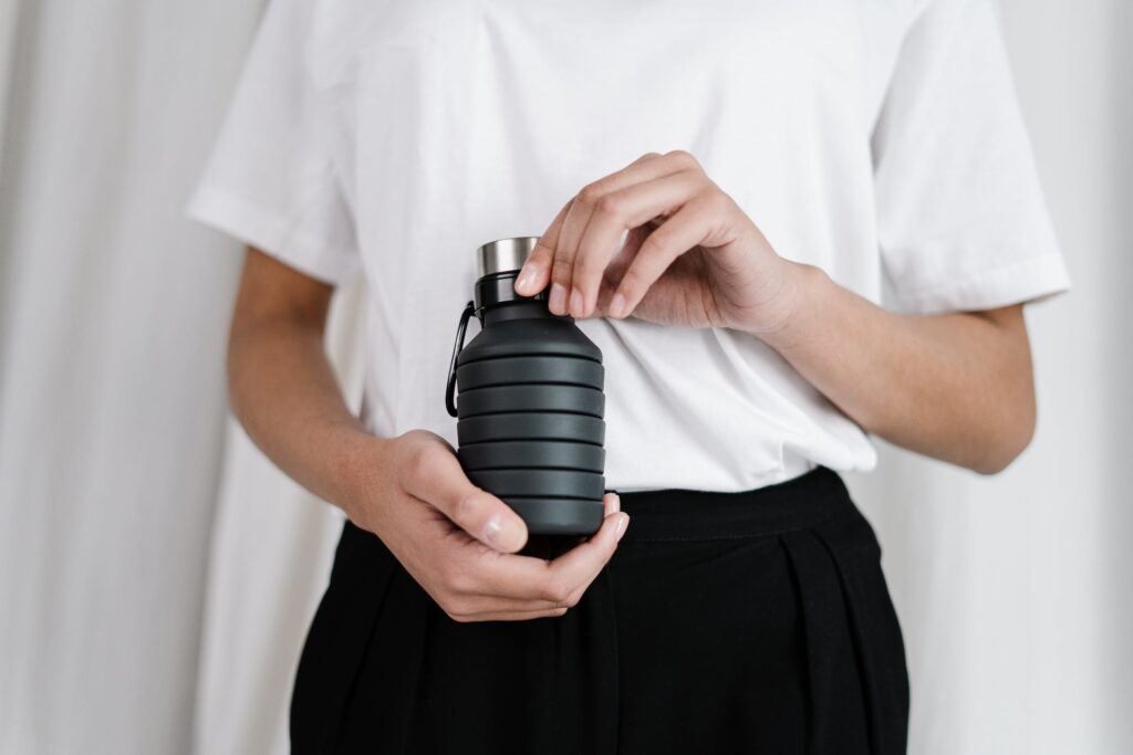 Woman's hands holding black collapsible water bottle