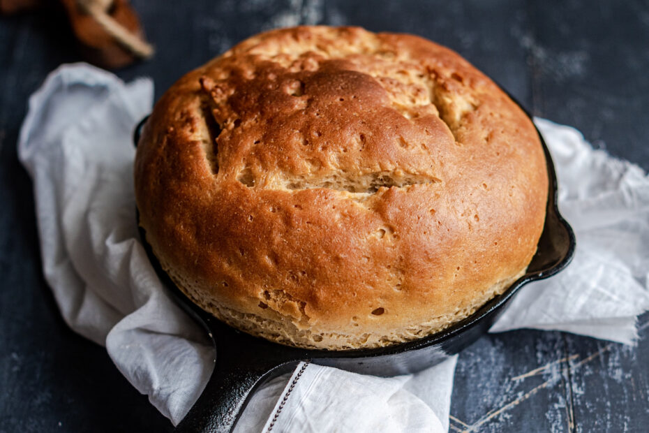 fresh baked bread in cast iron skillet with dish towel