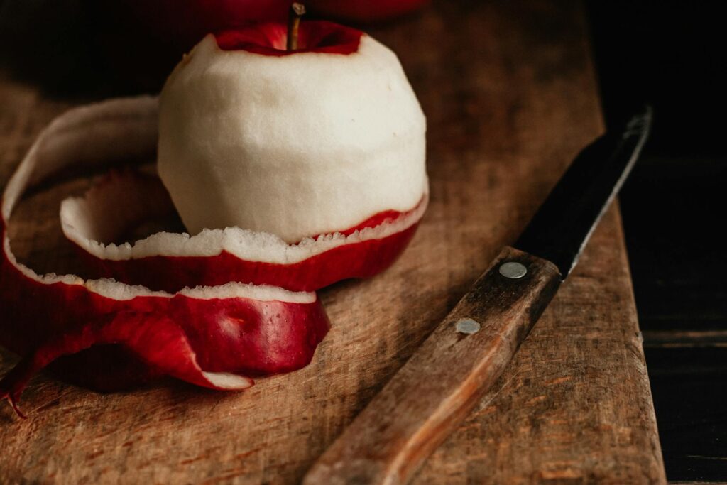 peeled red apple on cutting board with paring knife