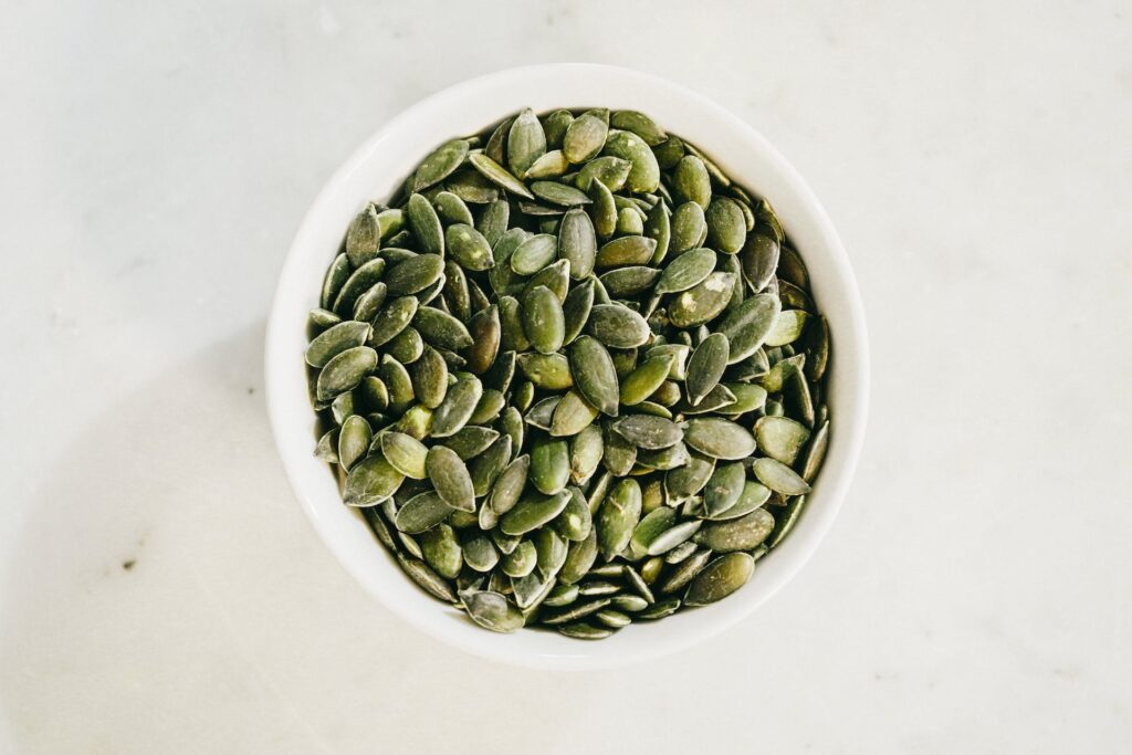 shelled pumpkin seeds in white bowl