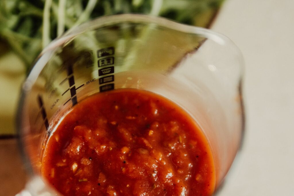 measuring cup with tomato sauce