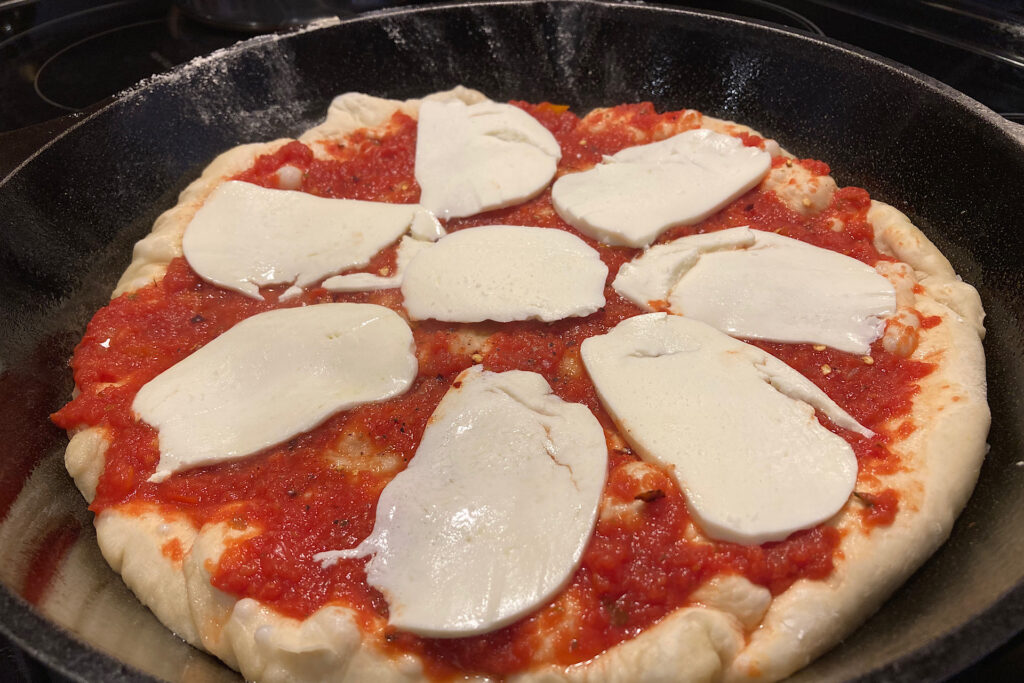 mozzarella cheese slice layer in crispy cast iron pizza prep