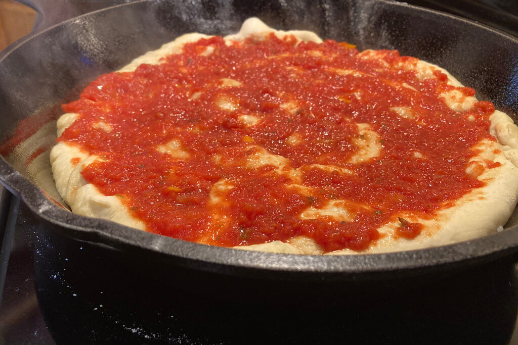 sauce spread on crispy cast iron pizza prep