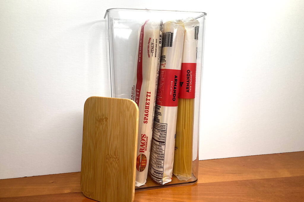 acrylic container with pasta packages inside for pantry organization