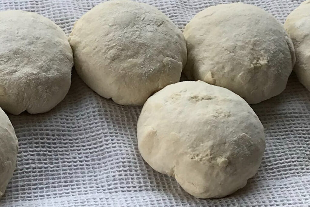 raw pizza dough balls on towel