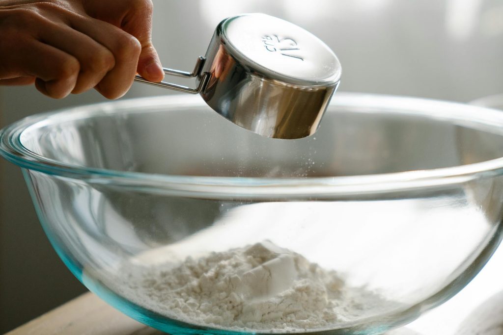 measuring cup dumping flour into bowl