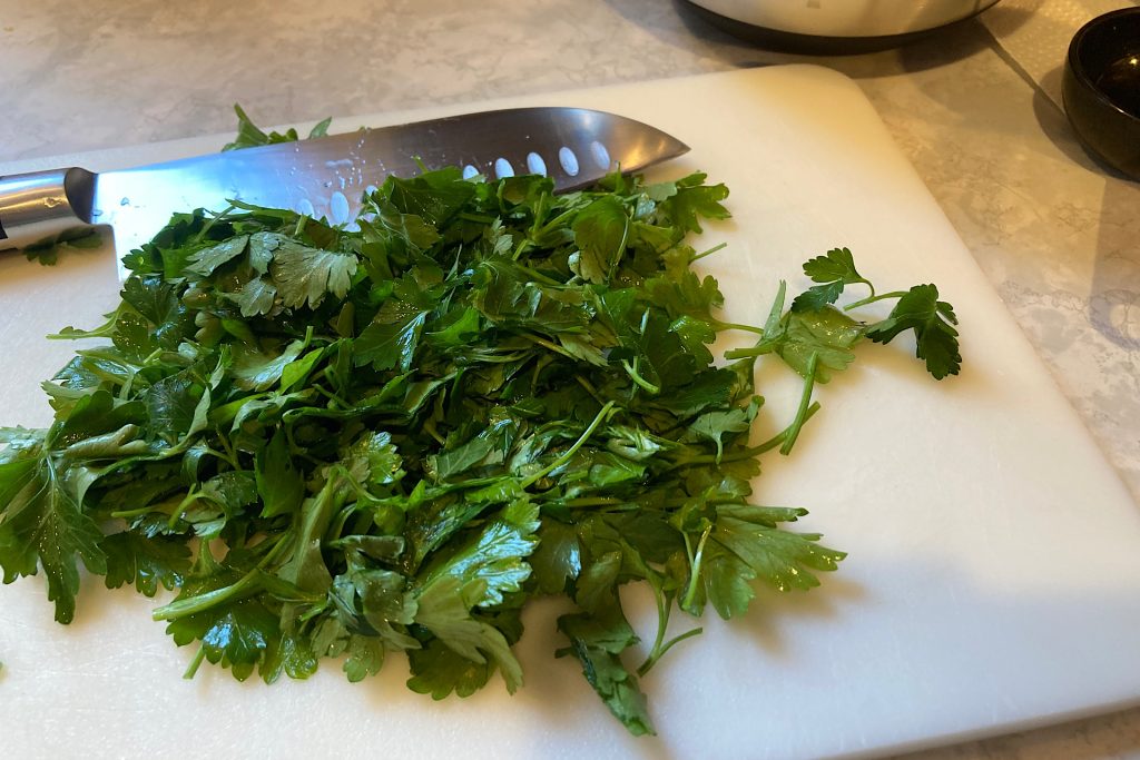 parsley on white cutting board with knife