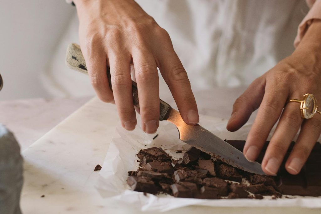 woman's hands chopping chocolate bar with a knife