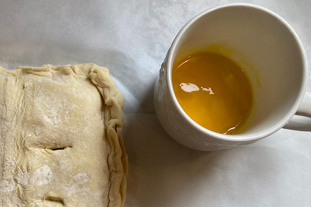 egg wash in teacup next to puff pastry