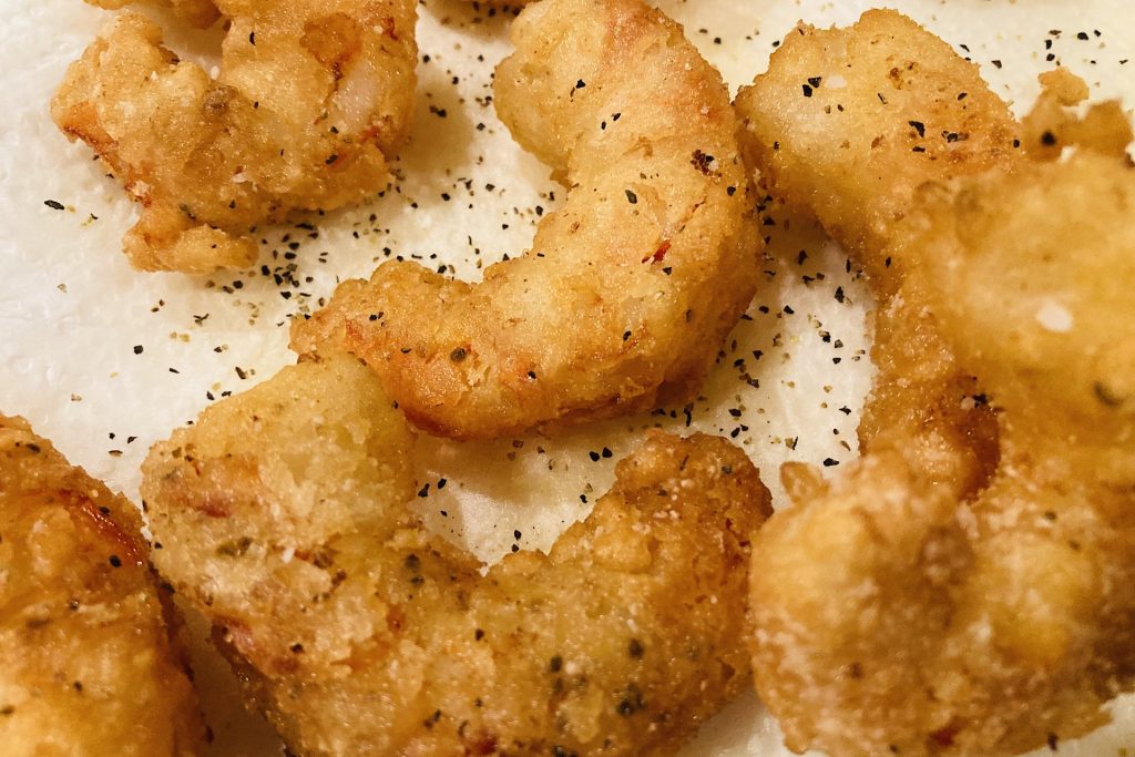 fried shrimp on paper towel sprinkled with salt and pepper