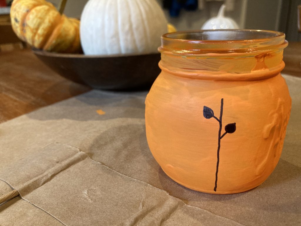 Adding leaves to vine on mason jar pumpkin lantern