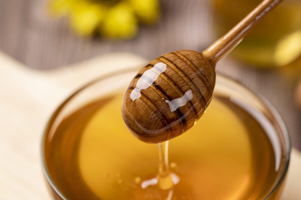 small bowl of honey with honey dripper