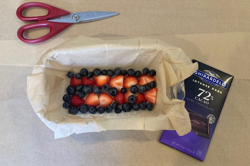 strawberries and blueberries in bottom of parchment lined loaf pan