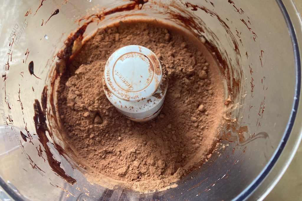 cocoa powder poured over batter in food processor
