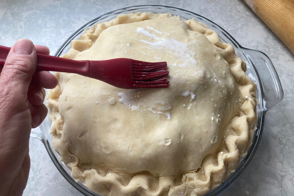 basting raw top of pie crust with half and half
