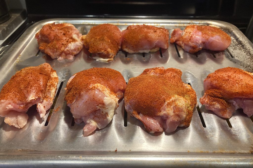 raw chicken thighs with paprika/cumin spice rub on broiler sheet pan