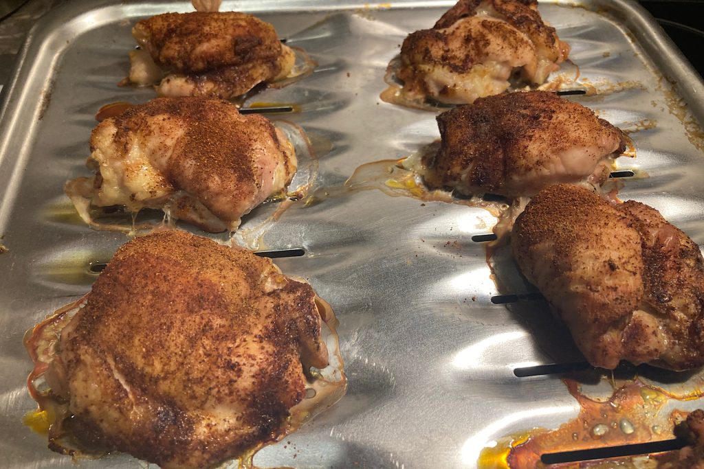 cooked chicken thighs seasoned with paprika/cumin on broiler sheet