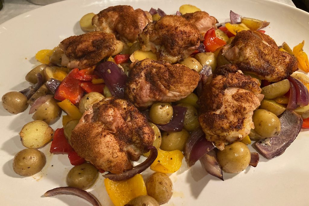 White platter with Sheet Pan Chicken Thighs Over Drip-Roasted Vegetables