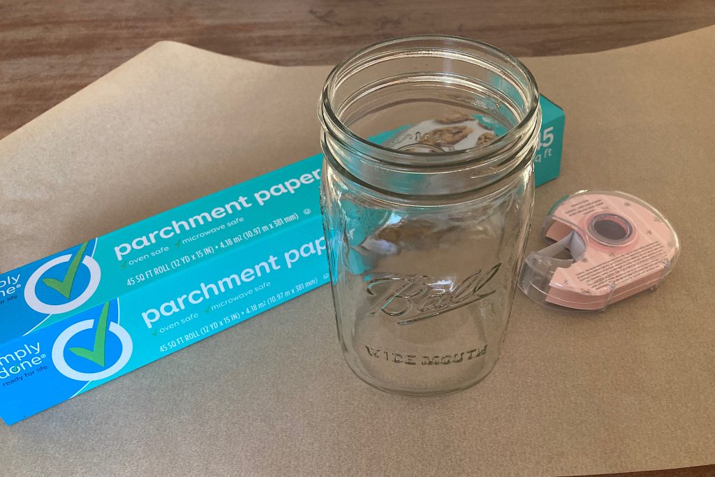 Parchment paper box, canning jar and scissors on a sheet of parchment paper