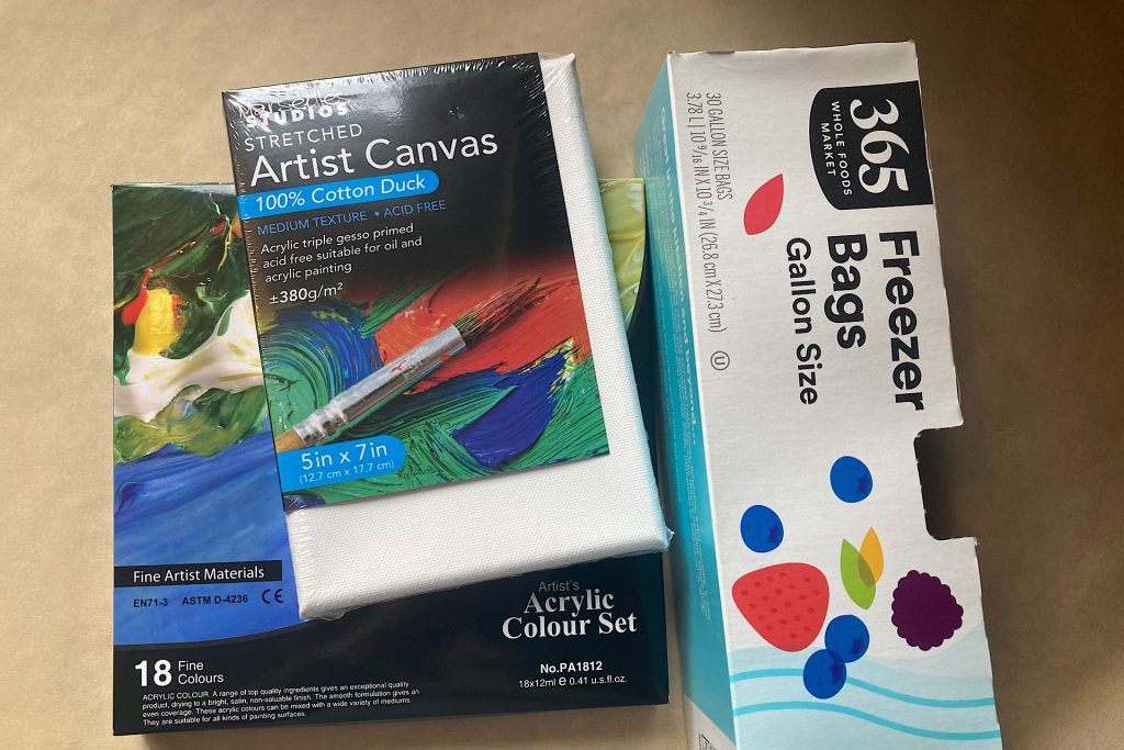 supplies for craft - plastic bags, 5x7 canvas, and box of acrylic paints