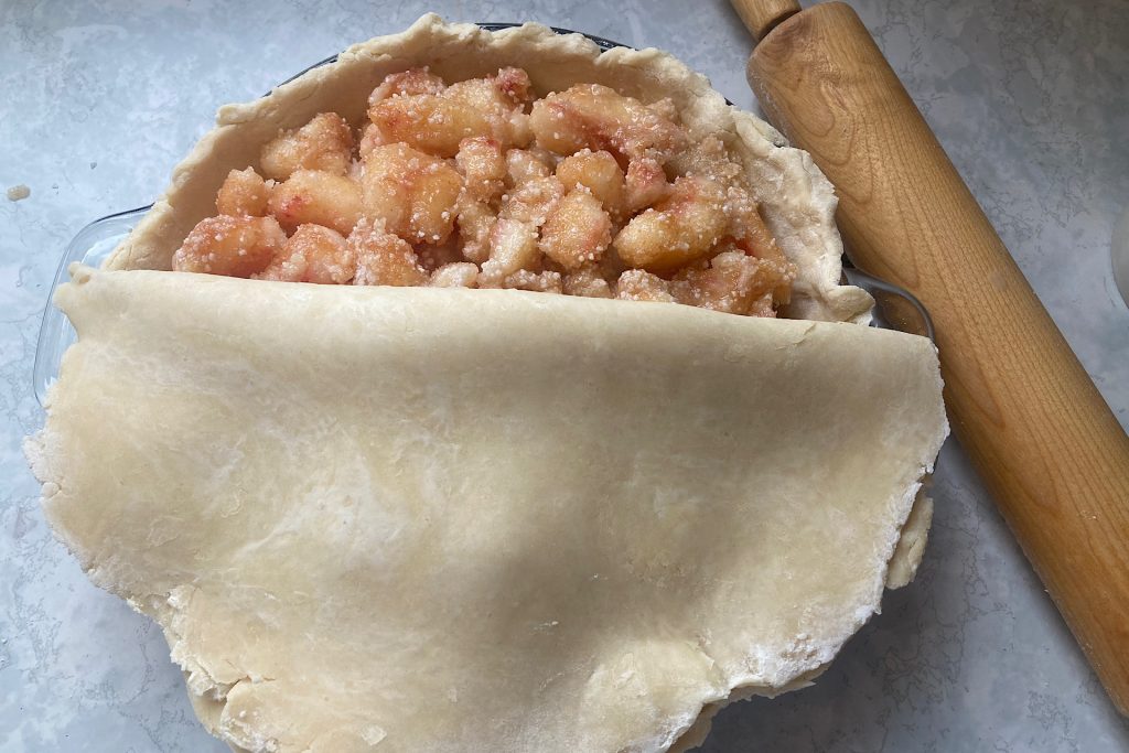 top crust folded in half on top of peach pie filling