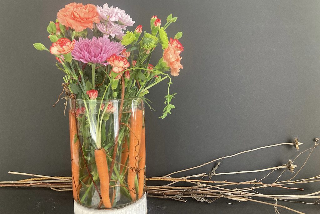 adding orange, green and violet flowers to glass vase