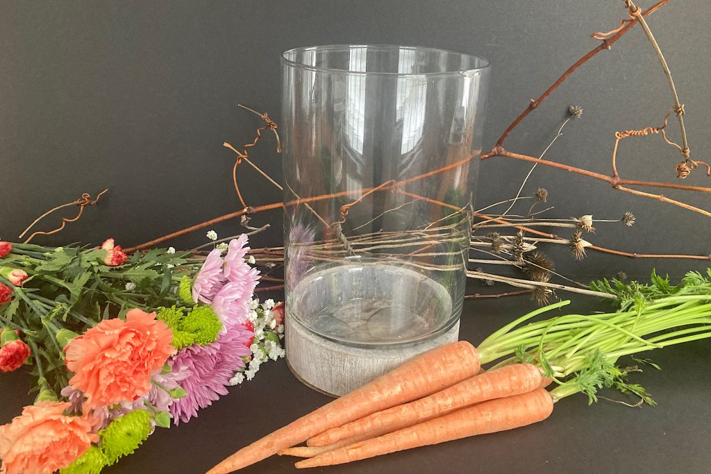 empty glass vase, bunch of flowers, bunch of carrots and twigs on tabletop