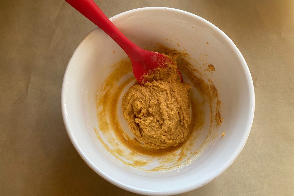 white mixing bowl with red spoon and sweet potato homemade dog biscuits batter