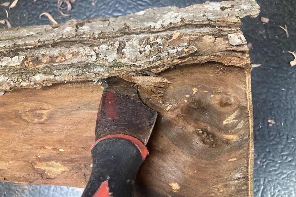 removing length of bark from a fireplace log with a putty knife