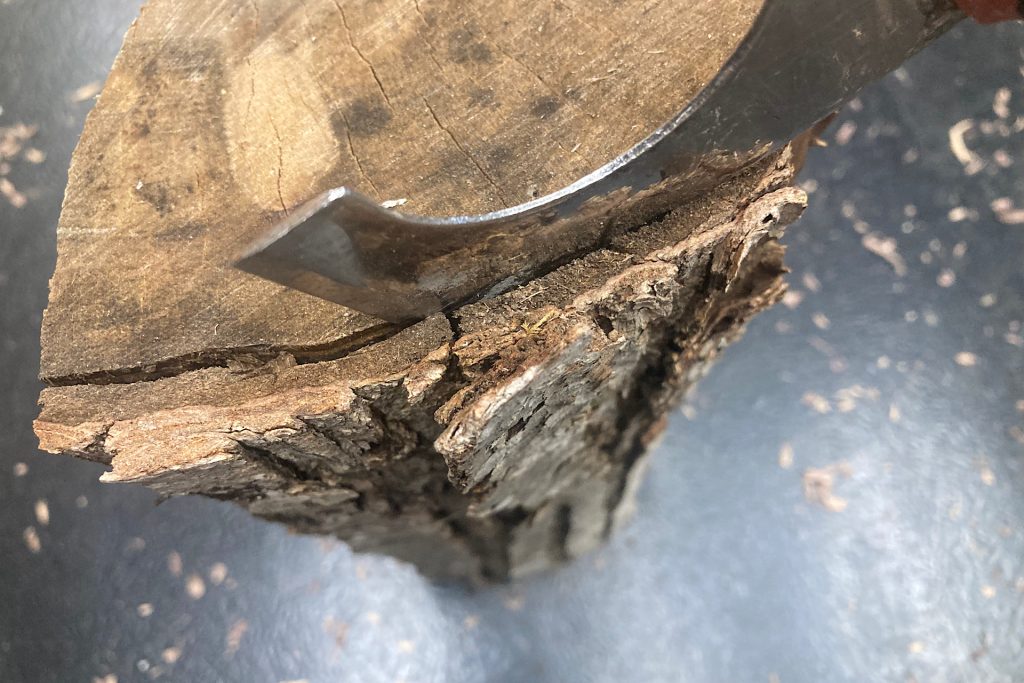 removing bark from fireplace log with a putty knife